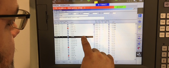 caucasian man pointing at a machine tool monitor