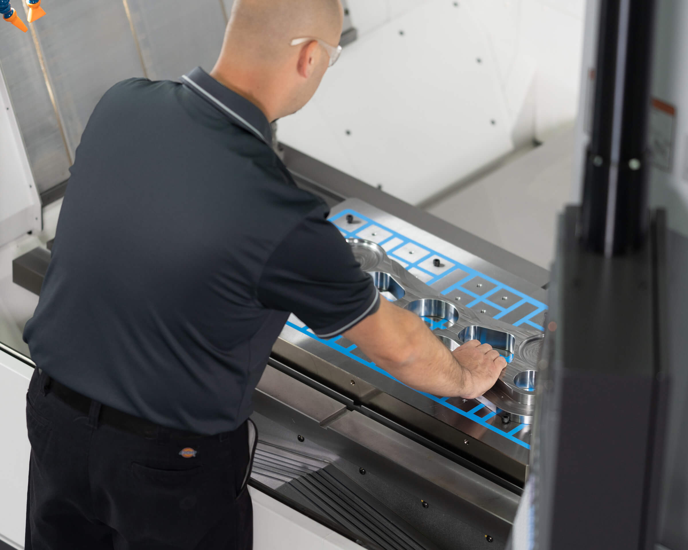 Operator ergonomically placing a part on the table of an Okuma machine